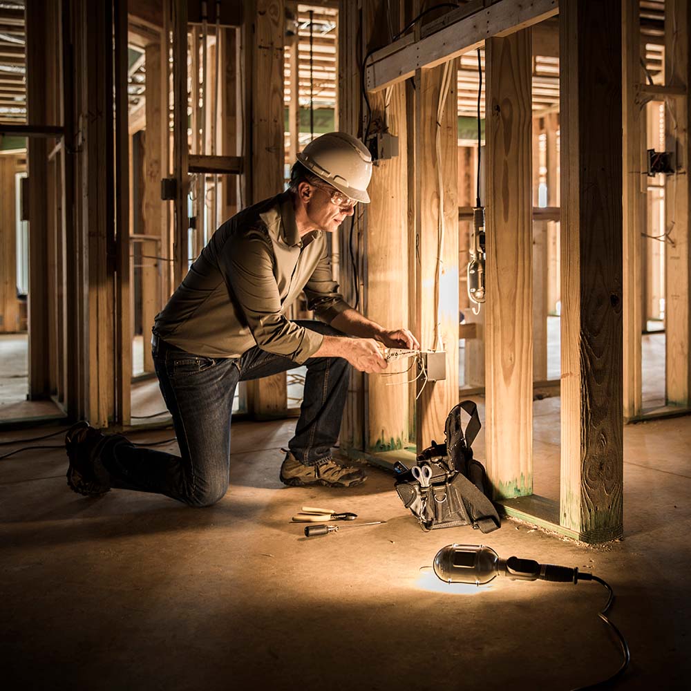 electrician working in framed house with dramatic lighting